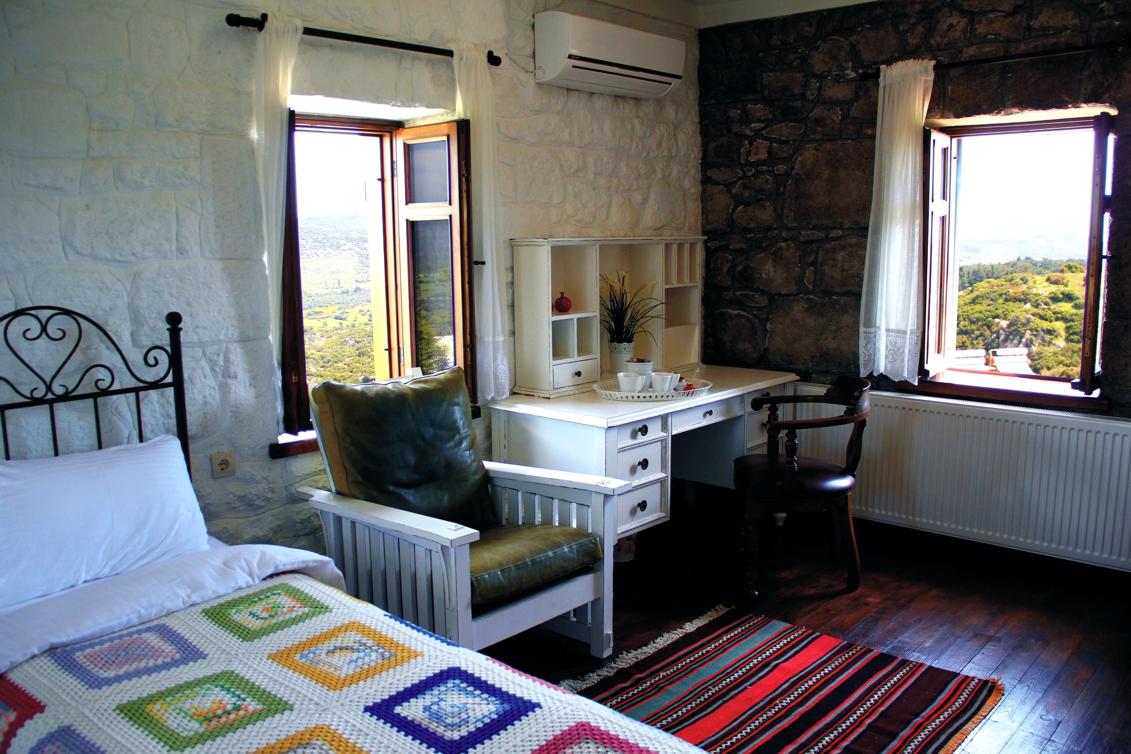 Un dormitorio con cama, escritorio, silla y vistas al exterior.