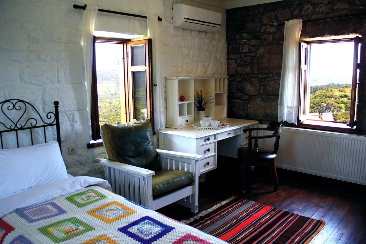 Un dormitorio con cama, escritorio, silla y vistas al exterior.
