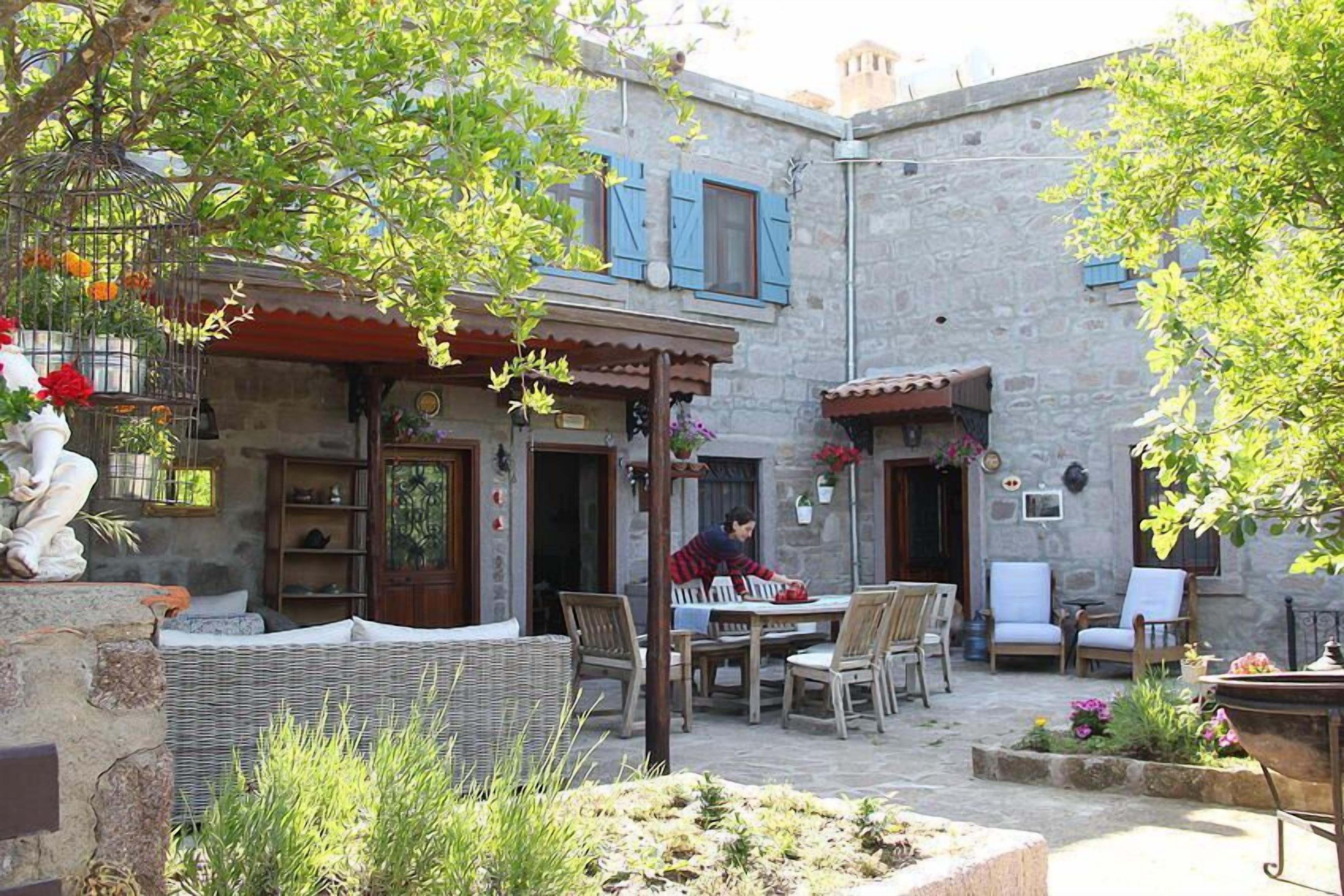A courtyard with outdoor seating, stone walls, and a person working at a table.