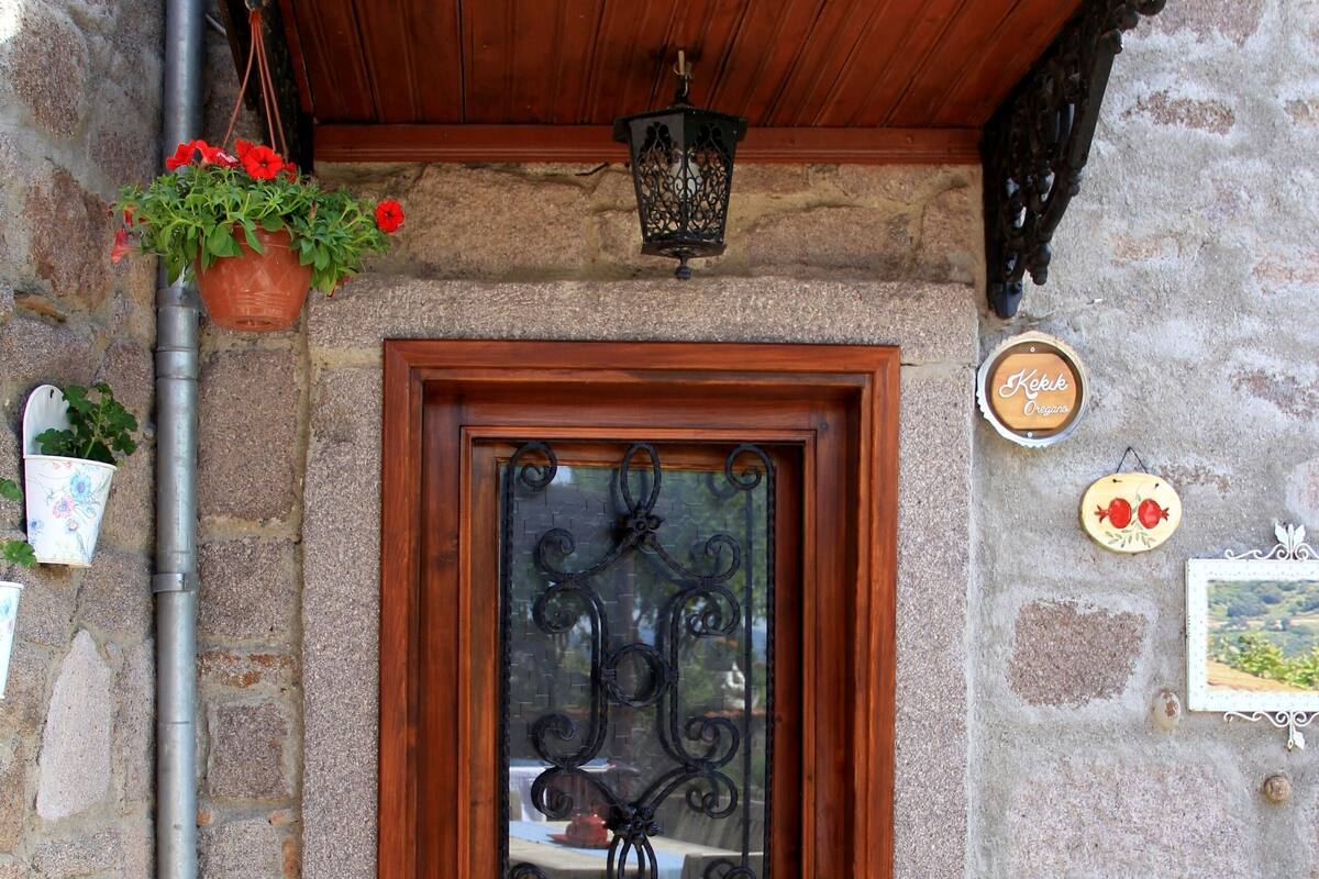A stone building with a wooden door, a metal lantern, and two clay pots.