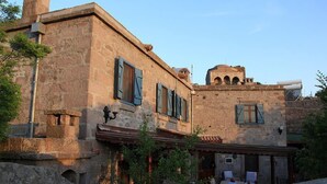 A stone building with traditional shutters, a small balcony, and a rustic appearance. - Assos Nar Konak (Ayvacik)