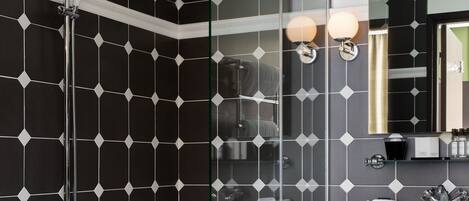 A modern bathroom with a glass-enclosed shower, a white bathtub, and a vanity with a mirror and sink.