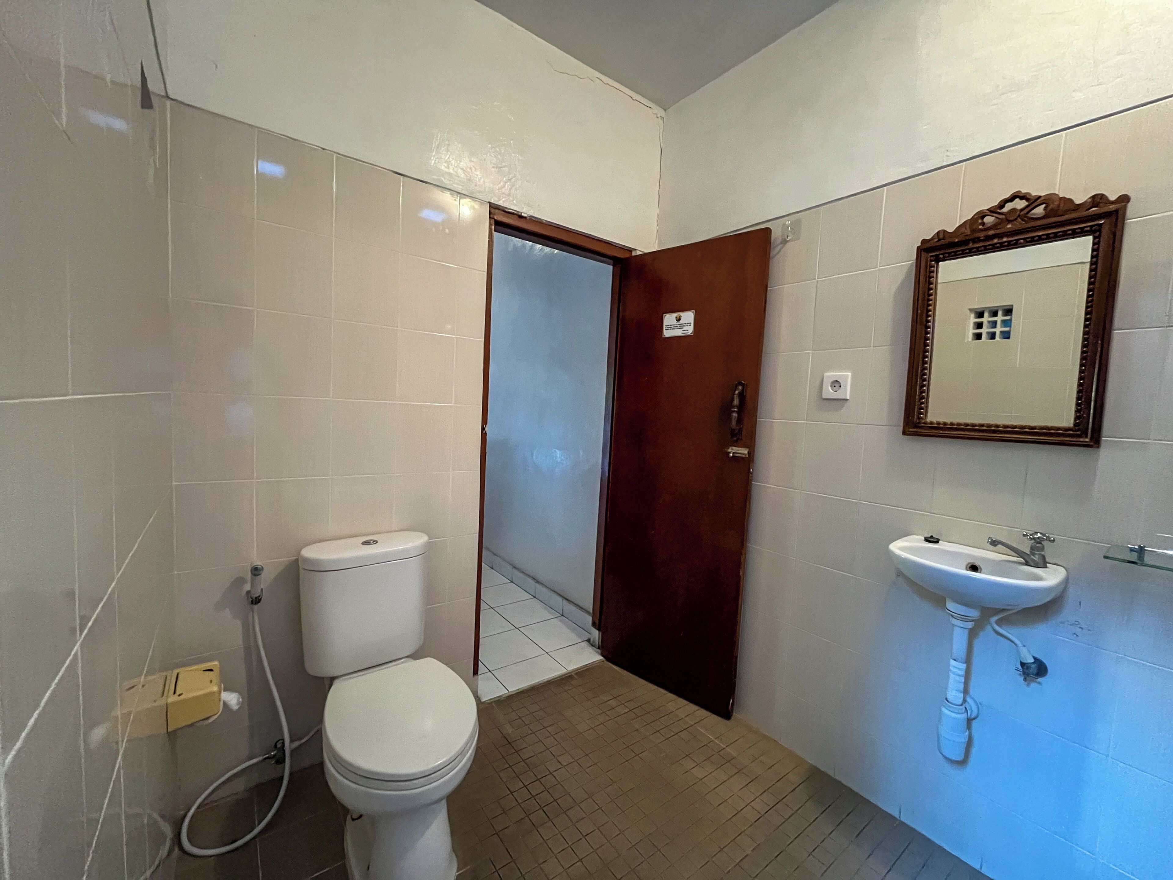 A bathroom with a toilet, sink, and mirror.