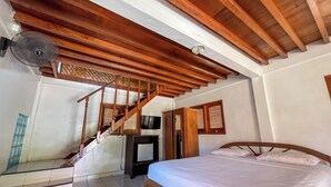Quarto com escada de madeira, cama, televisão e ventilador de teto.