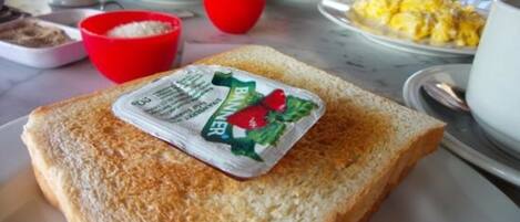 A breakfast setting with toast, a red bowl, and a plate of scrambled eggs.