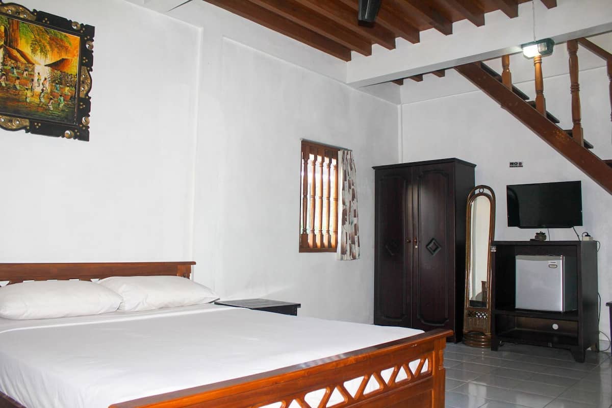 A bedroom with a bed, a wardrobe, a television, and a staircase.
