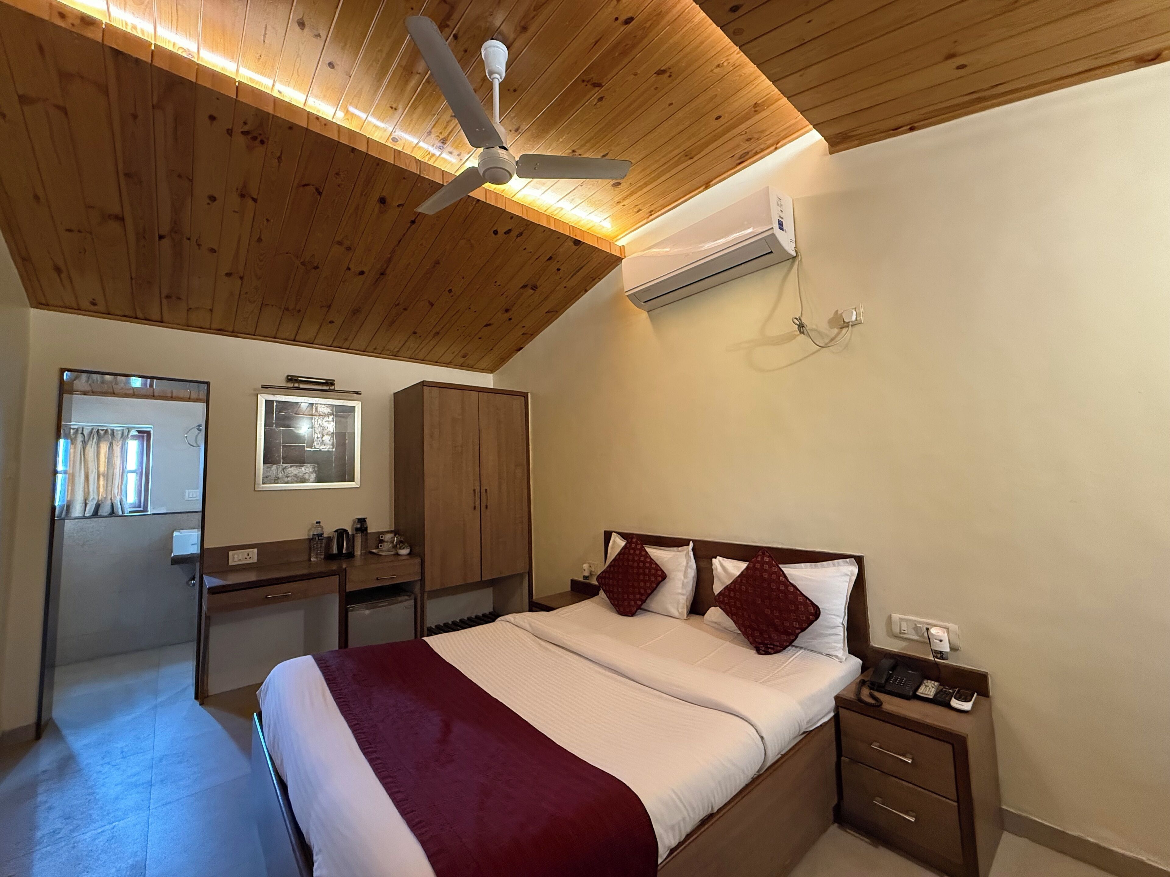Un dormitorio con cama, escritorio, armario, ventilador de techo y aire acondicionado.