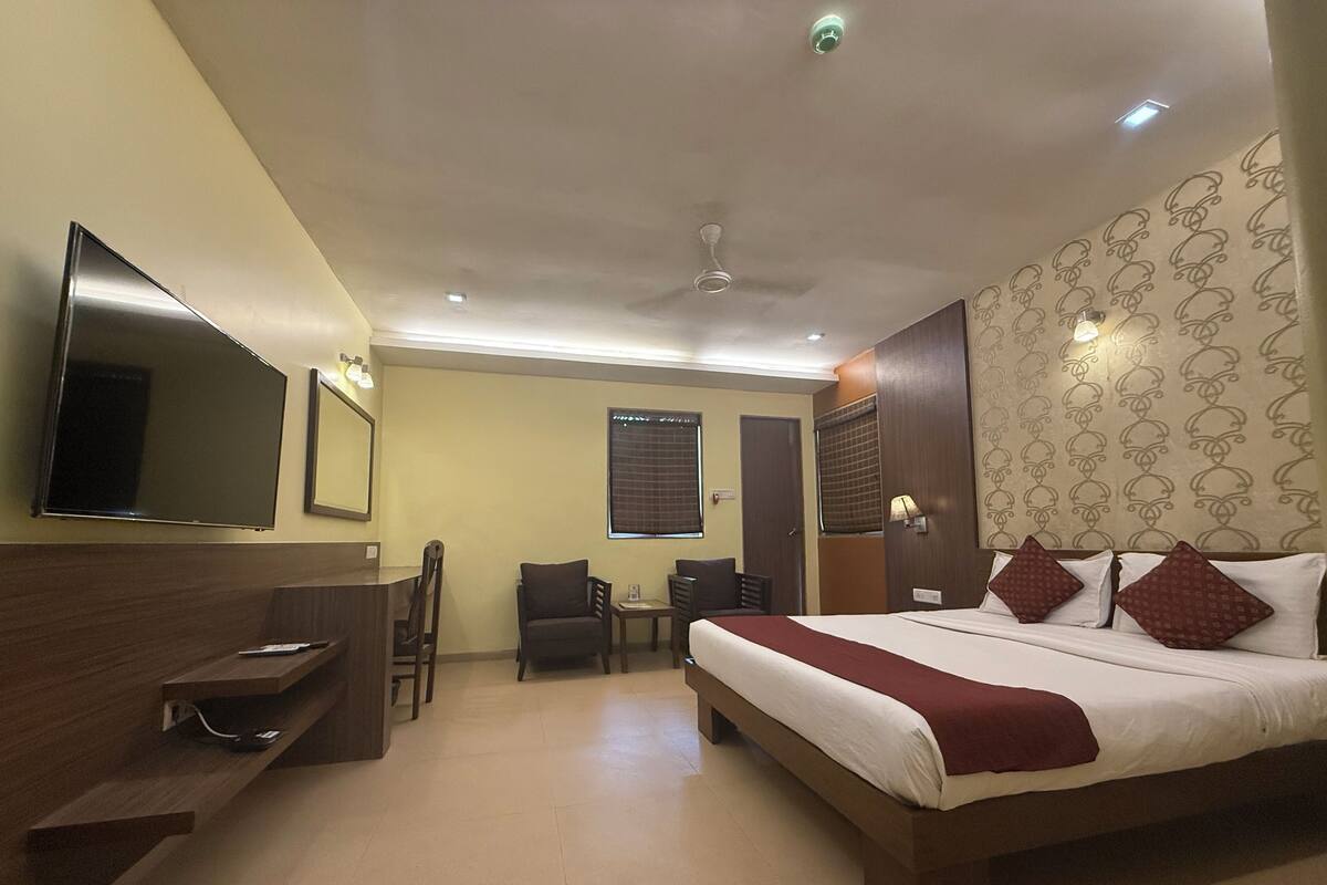 Ein Hotelzimmer mit einem großen Bett, einem Schreibtisch, einem Sessel, einem Fernseher und einem Deckenventilator.