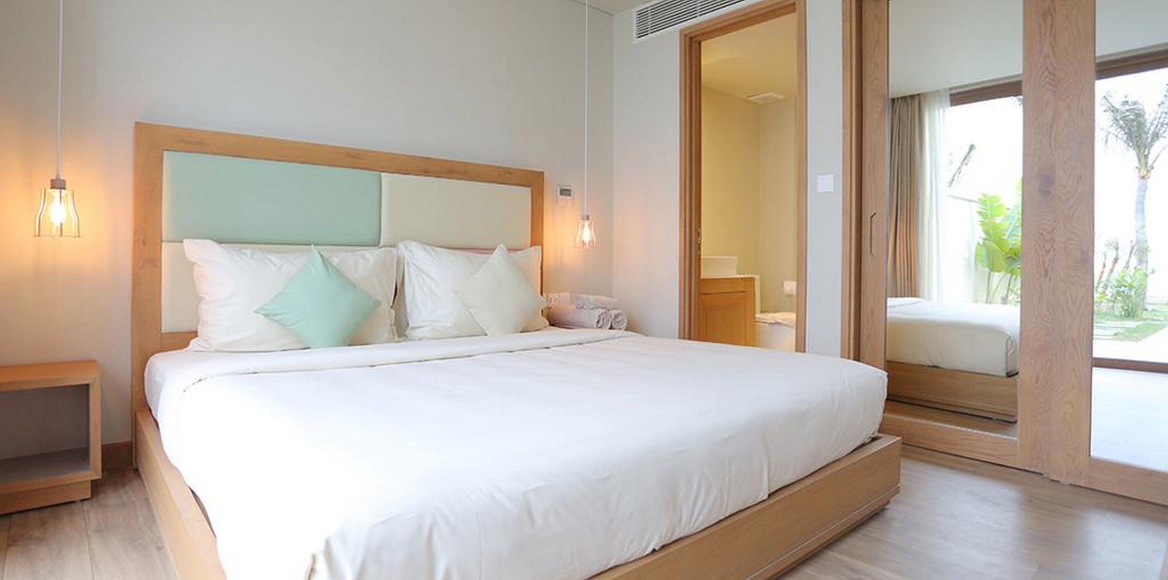 Une chambre moderne avec un grand lit, une tête de lit en bois et une vue sur un balcon.