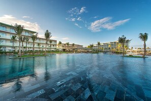 A hotel with a large infinity pool, palm trees, and a clear blue sky. - FLC Luxury Hotel Samson (Sam Son)