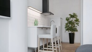 Una cocina moderna con armarios blancos, una campana extractora negra y una planta en maceta.