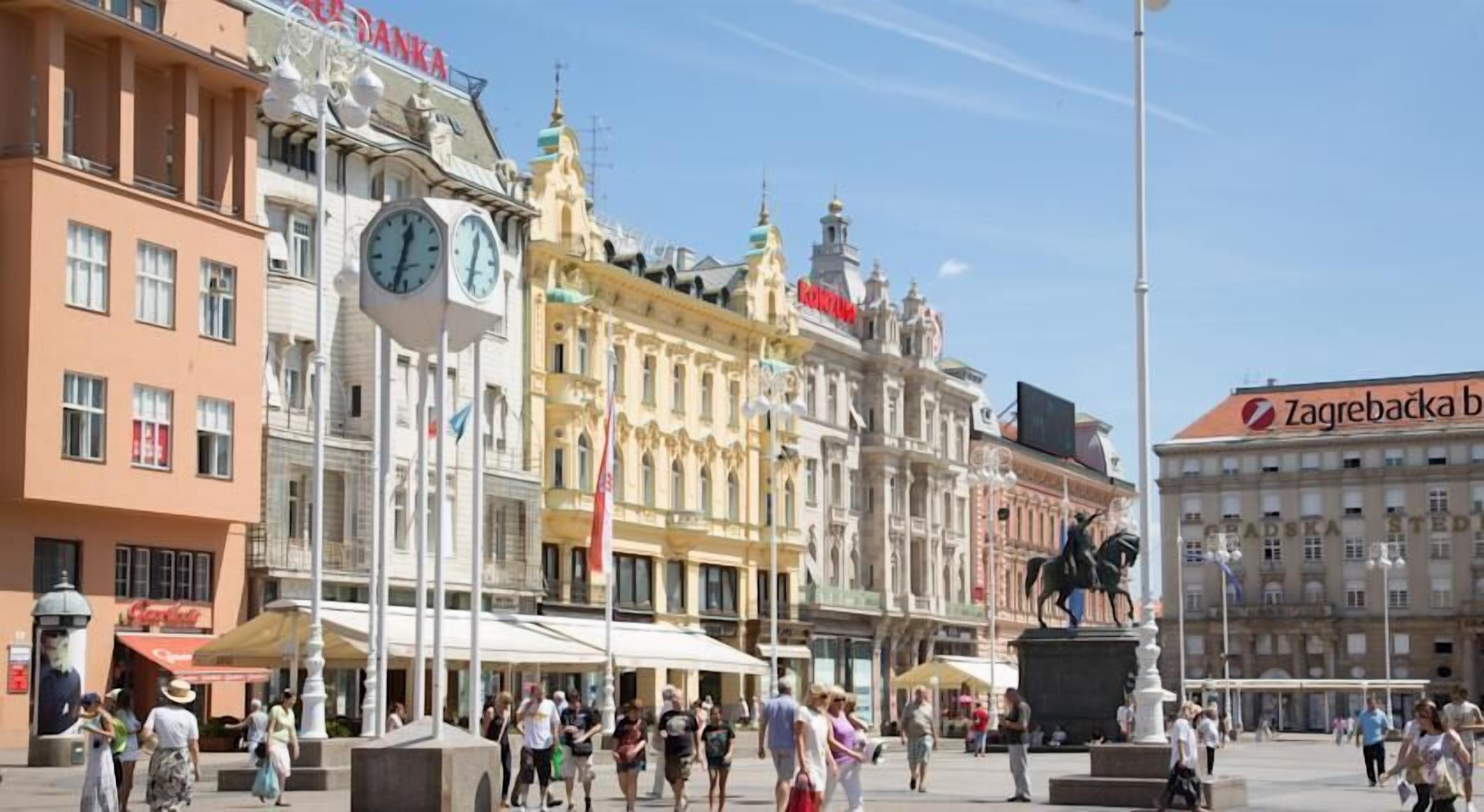 A public square with historic buildings, a statue, and a clock tower.