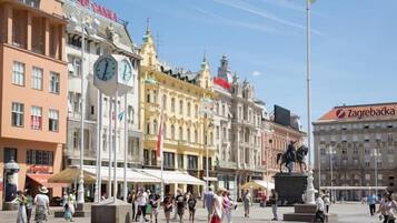 Uma praça pública com edifícios históricos, uma estátua e um campanário.