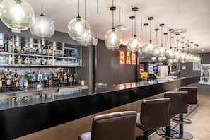 A bar area with a long counter, multiple hanging light fixtures, and bar stools. - Premier Inn Braunschweig City Centre (Braunschweig)