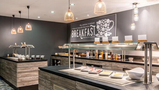 A breakfast bar with a modern design, featuring a dark wall, wooden counter, and pendant lighting.