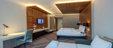 A hotel room with a bed, a desk, a chair, a TV, and a bathroom.