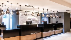 A hotel reception area with black reception desks, hanging light fixtures, and a wall with motivational phrases.