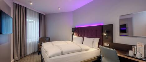 Habitación de hotel con cama, escritorio, silla, televisor y señalización de servicios de comida y bebida.