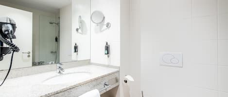 A modern bathroom with a large mirror, two sinks, a hairdryer, and a towel rack.