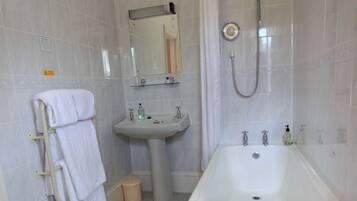 Un baño con bañera, lavamanos, espejo y toallero.