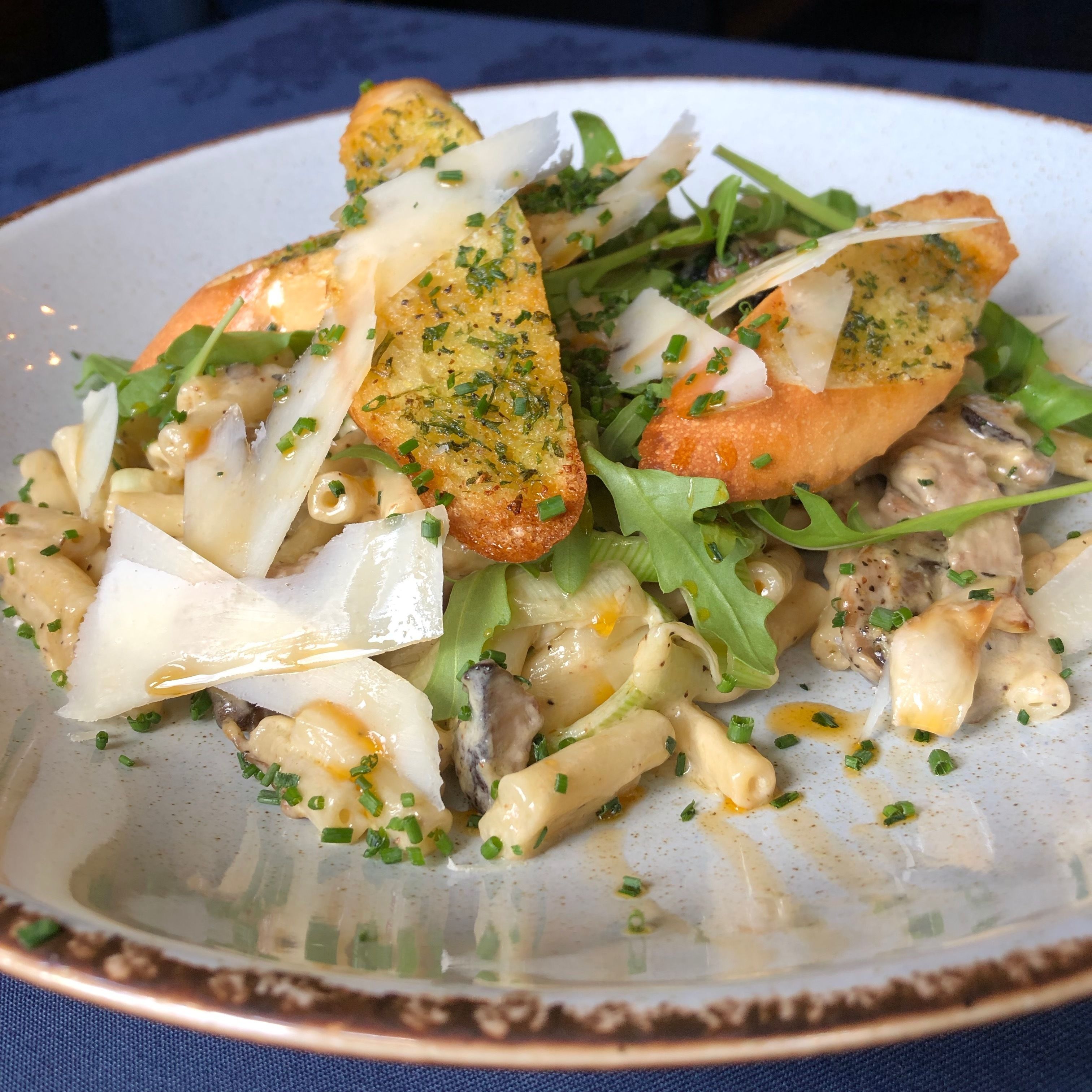 A plate of food with pasta, greens, and cheese.