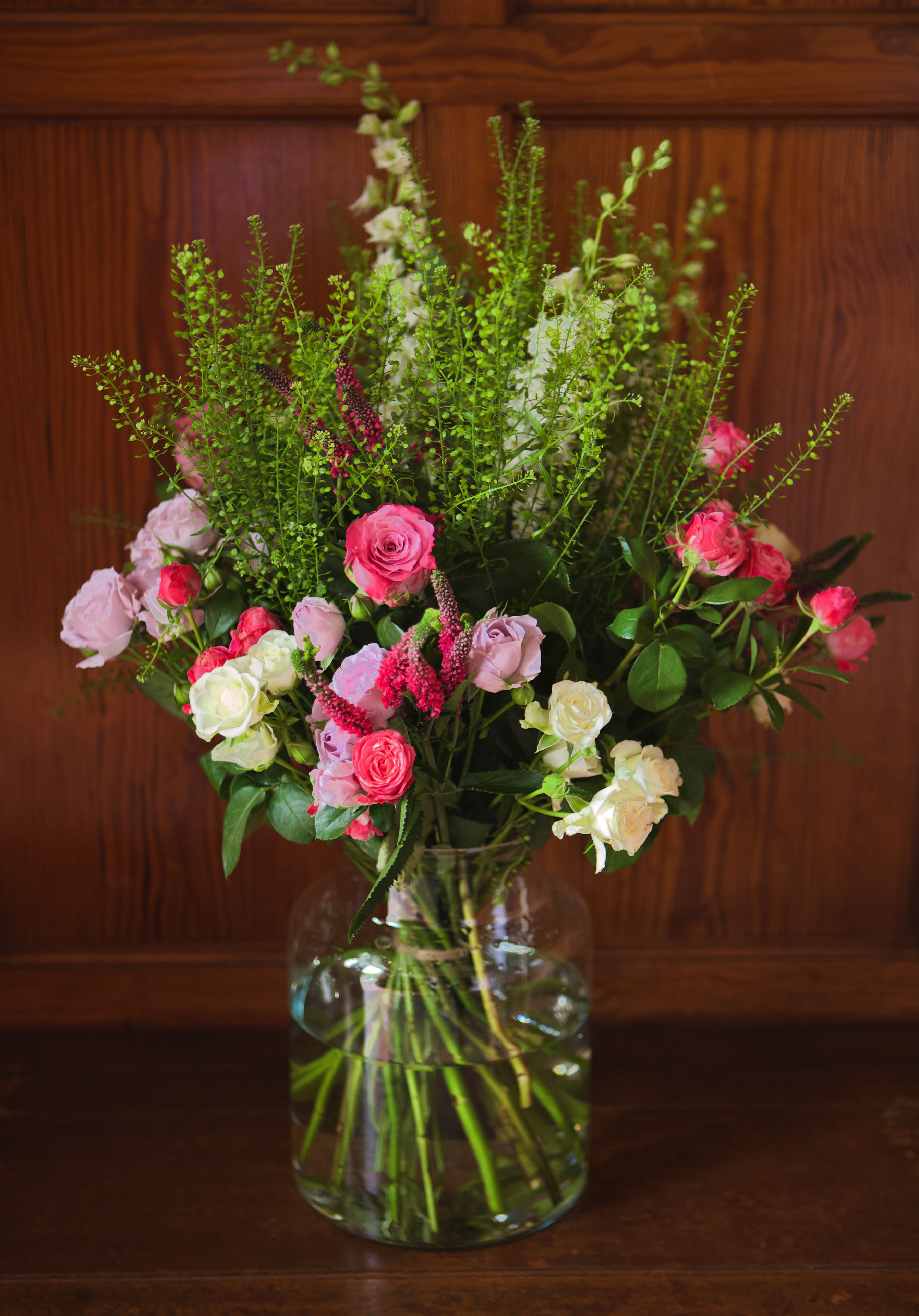 Un ramo de flores en un jarrón de vidrio sobre una mesa de madera.