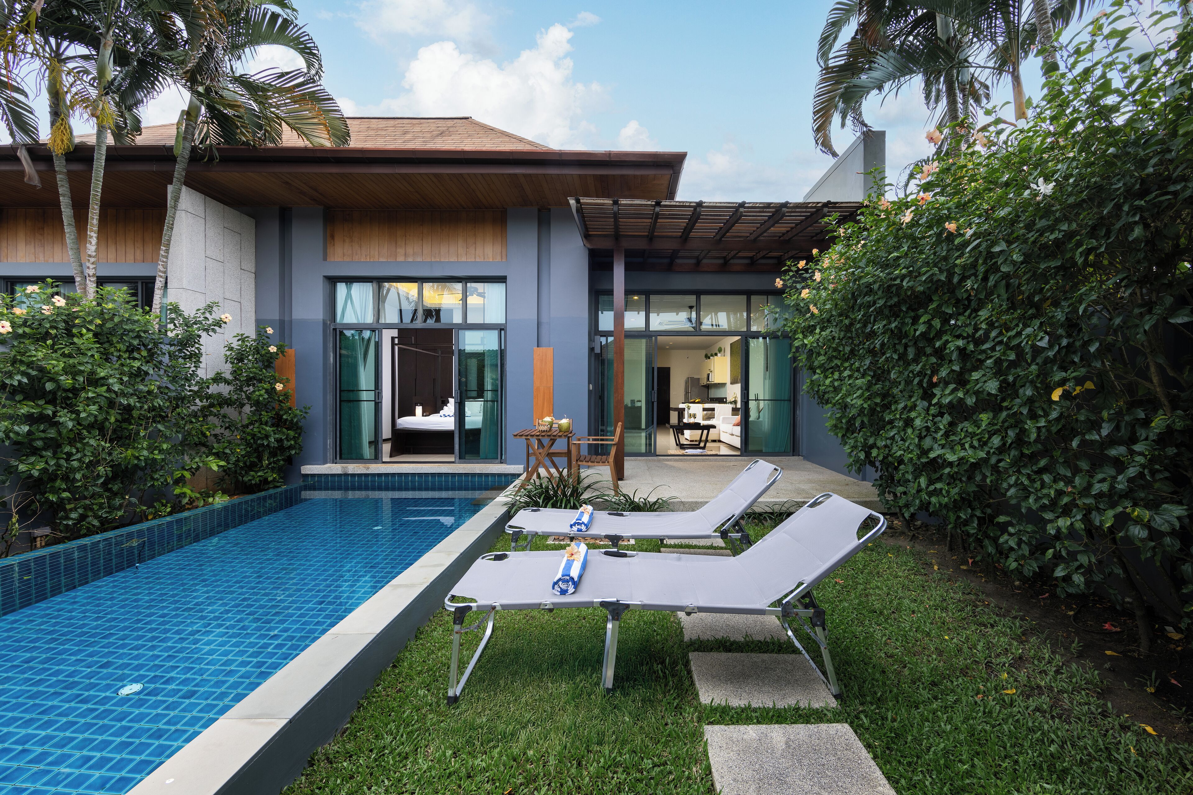 A modern house with a swimming pool, lounge chairs, and a patio area.