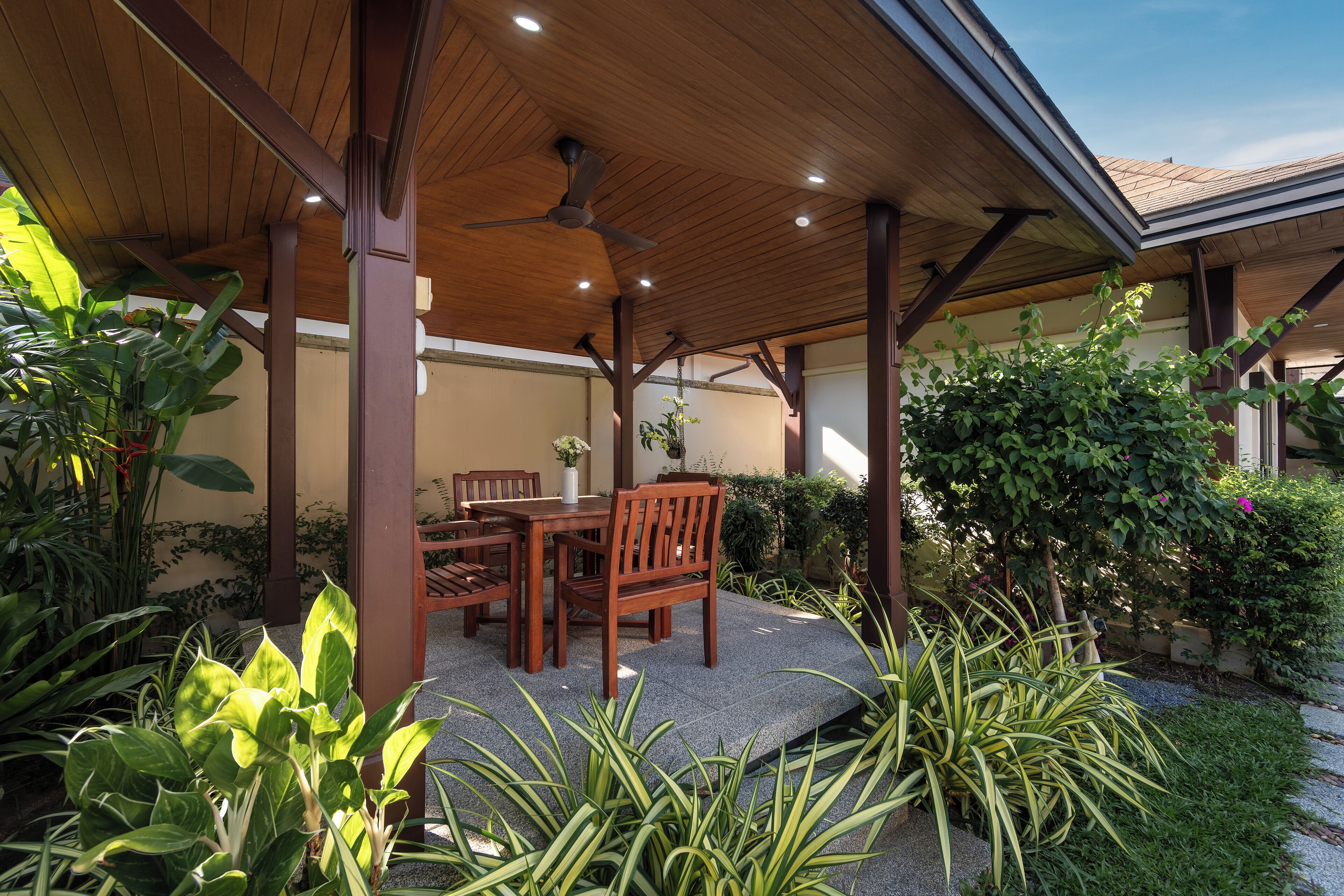An outdoor patio with wooden furniture and potted plants.