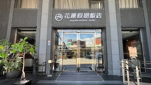 L’entrée de l’hôtel Hualien Holiday, dotée d’un design moderne, se caractérise par une porte en verre, des rampes en métal et un pot de fleurs.