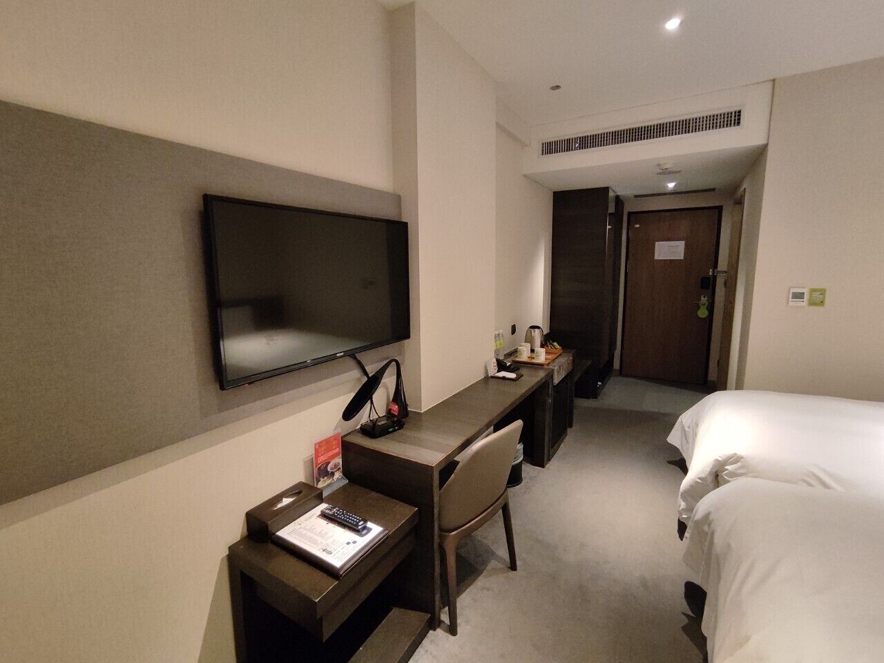 Une chambre d’hôtel avec un lit, un bureau et une chaise, une télévision et une porte.
