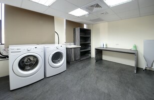 A laundry room with two front-loading washers, a sink, and a bench.