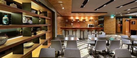 A modern restaurant with wooden shelves, tables, and chairs.
