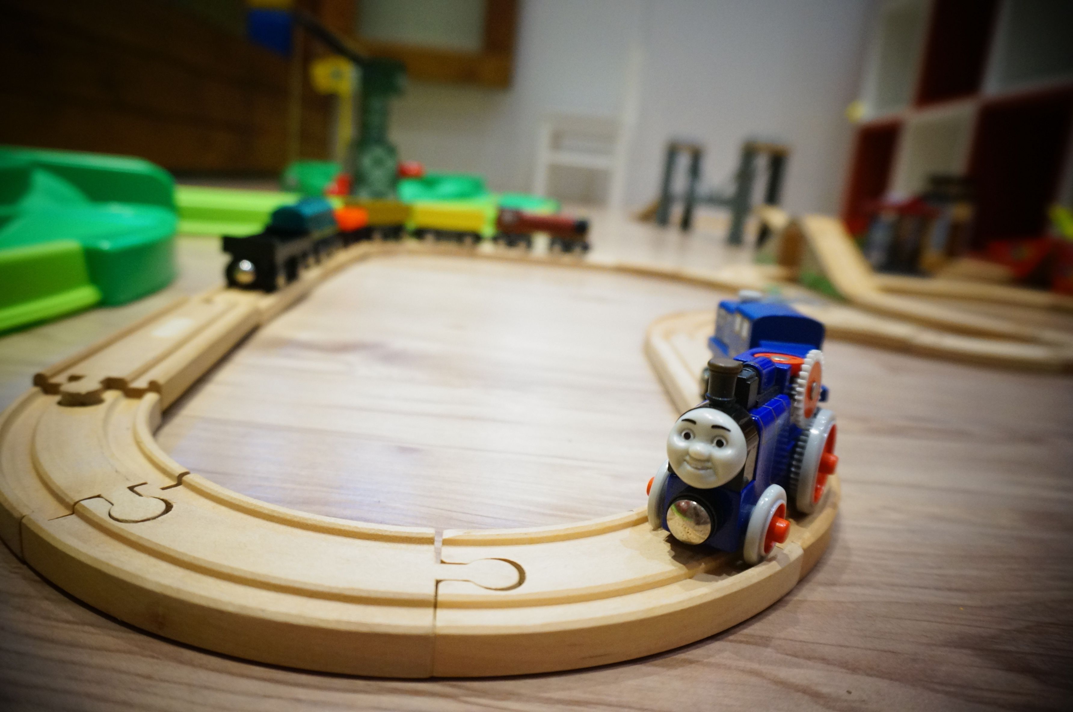 A wooden toy train track with a Thomas the Tank Engine model on it.