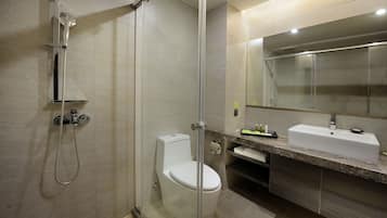 A modern bathroom with a glass-enclosed shower, a toilet, and a sink with a mirror above it.