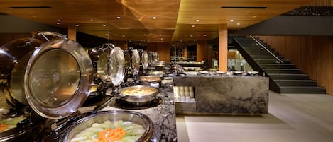 A buffet area with multiple serving stations, a marble counter, and a staircase leading to an upper level.