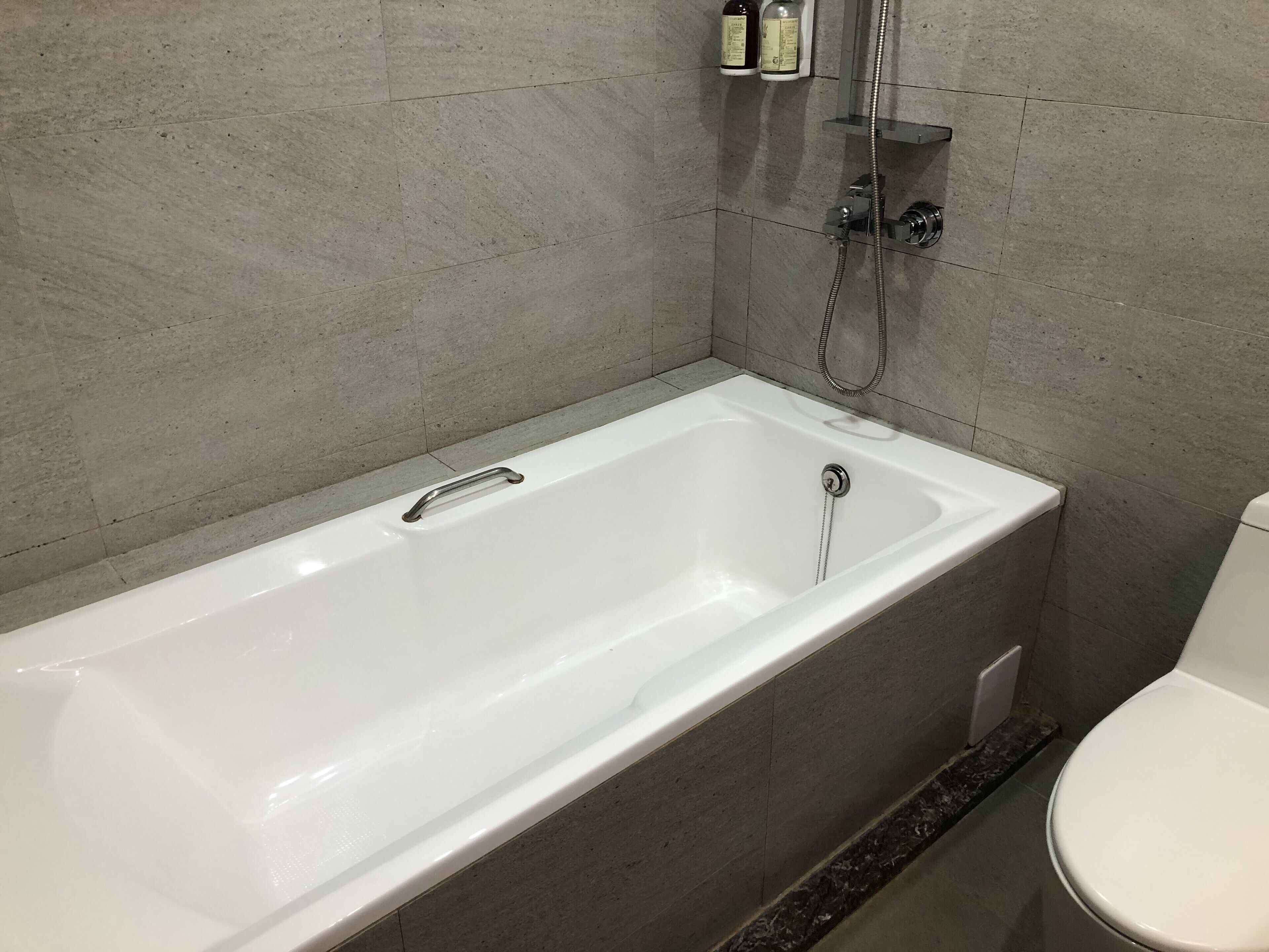 A modern bathroom with a white bathtub, a shower, and a toilet.