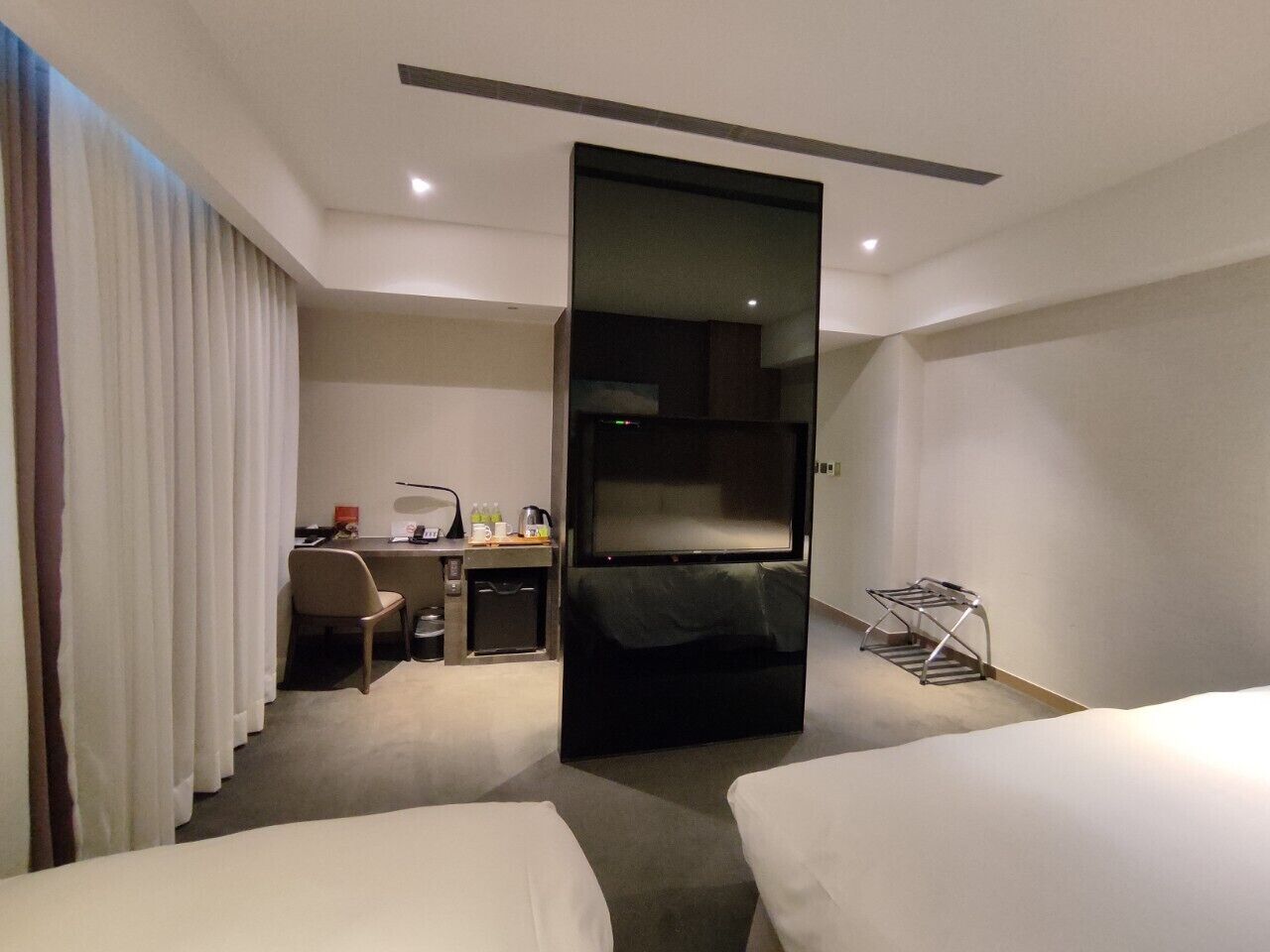 Una habitación de hotel con dos camas, un escritorio, una silla, un televisor y un armario.