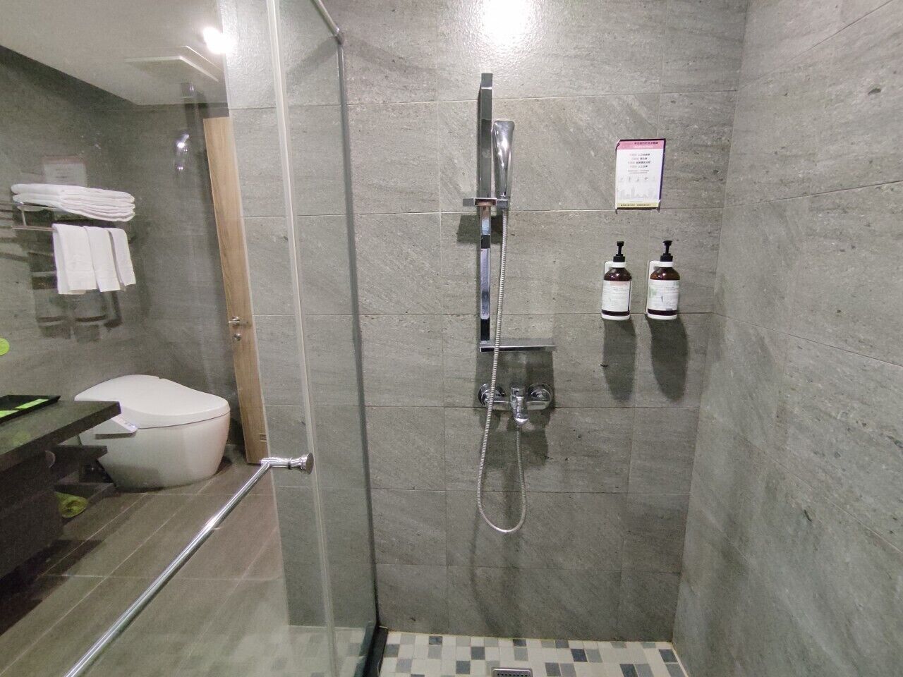 Une salle de bain moderne avec une douche à parois de verre, des toilettes et un lavabo équipé d’un porte-serviettes.