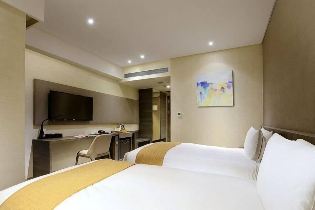 Ein Hotelzimmer mit Bett, Schreibtisch, Stuhl, Fernseher und einem Bild an der Wand.