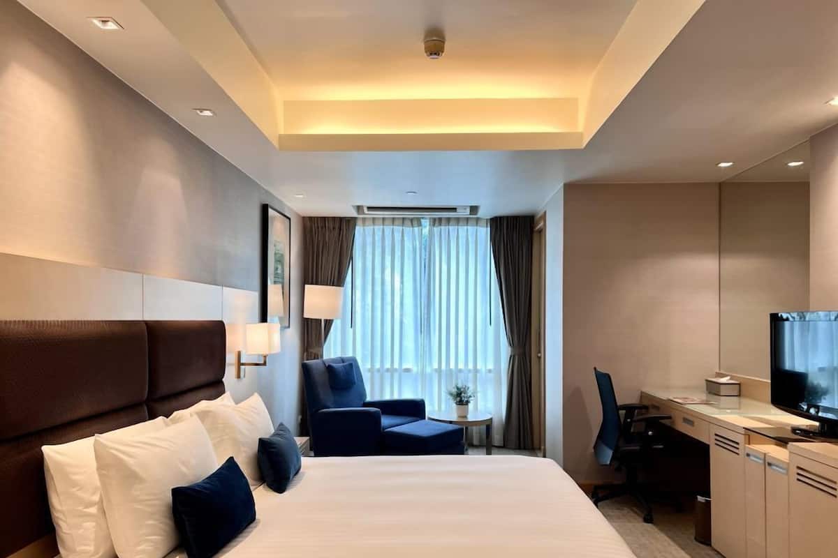 Una habitación de hotel con una cama grande, un escritorio, una silla y un televisor.