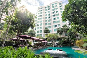 Un hôtel doté d’une piscine, entouré d’une végétation luxuriante et de palmiers.