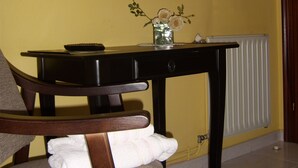 A room with a wooden chair, a small table with a vase of flowers, and a radiator. - Pensión Residencia Tambre (Santiago de Compostela)