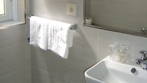 A bathroom with a white sink, two white towels hanging on hooks, a mirror, and a window. - Pensión Residencia Tambre (Santiago de Compostela)