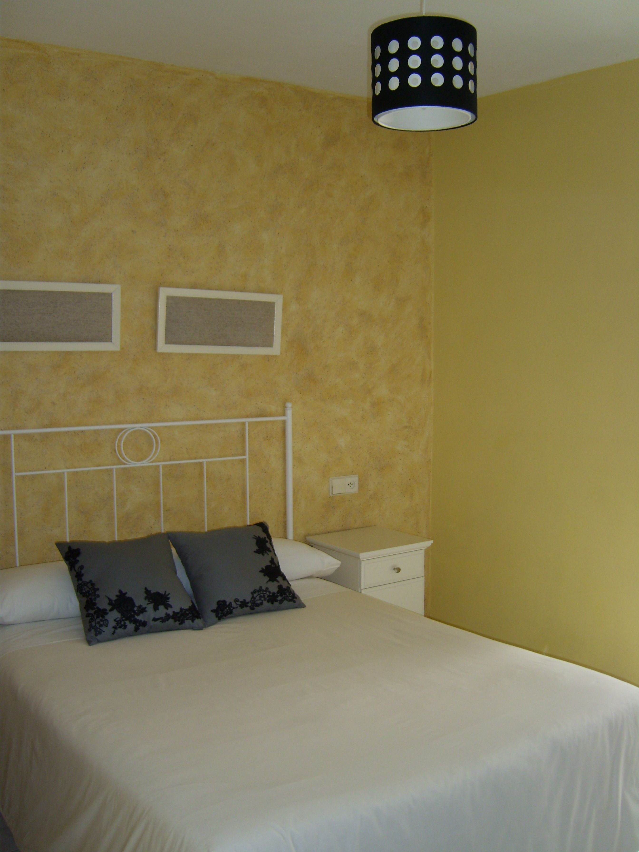 Ein Schlafzimmer mit einem Bett, zwei Nachttischen, einer Wandleuchte und zwei gerahmten Bildern.