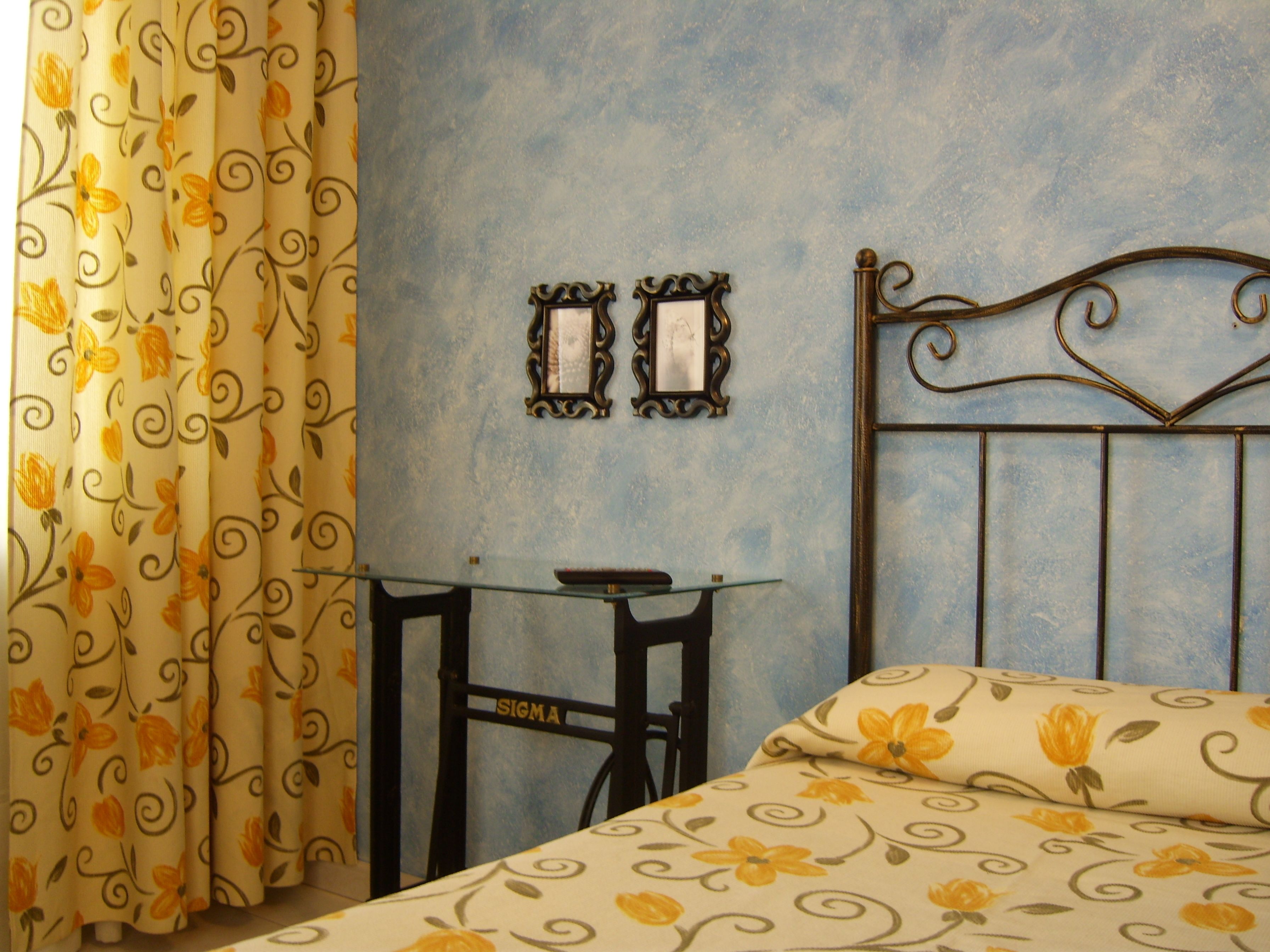 Een kamer met een bed, een tafel en gordijnen.