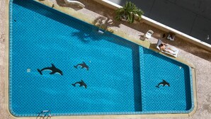 A swimming pool with dolphin tiles and a palm tree.
