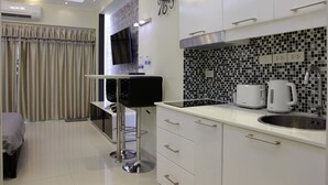 A modern kitchen with a flat-screen TV, a coffee maker, and a tiled backsplash.