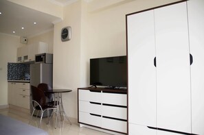 Ein kompakter Wohnraum mit Küchenzeile, einer Essecke mit Tisch und Stühlen sowie einem Schrank mit Fernseher.
