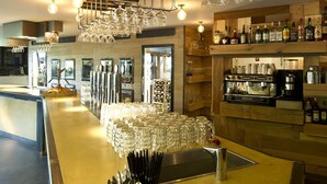 Una zona de bar con mostrador, vasos y botellas.