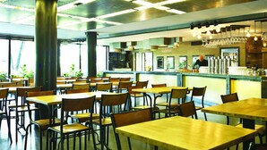 Una amplia cafetería con techos altos, conductos expuestos y una zona de bar con un cantinero.